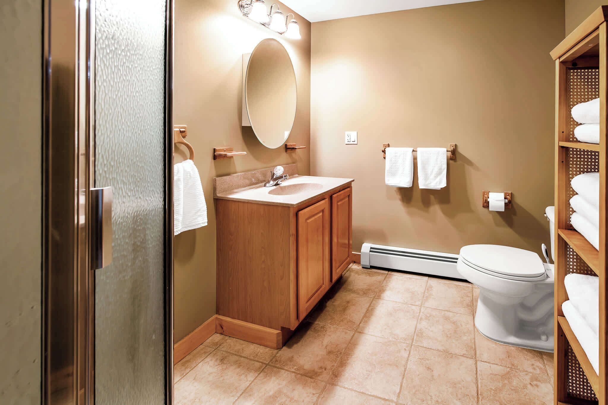 Une salle de bain avec un meuble-lavabo en bois, des toilettes blanches et un porte-serviettes.