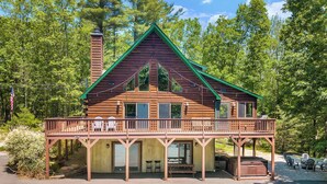 Une cabane en rondins avec un toit végétalisé, un balcon et une terrasse.