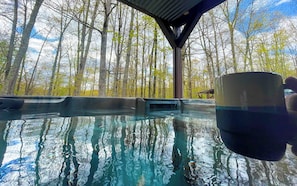 A clear pool with reflections of trees and a wooden structure overhead. - Massive Log Chalet With Hot Tub (Lakeville)