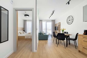 Un appartamento moderno con zona pranzo, divano, letto e cucina.