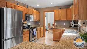 Una cocina moderna con armarios de madera, electrodomésticos de acero inoxidable, encimeras de granito y una isla central.