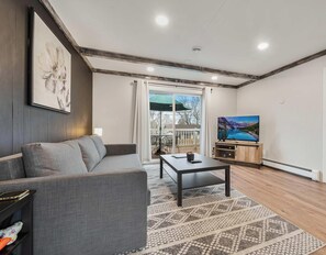 A living room with a sofa, coffee table, TV, and artwork.