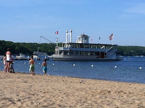 Ein Flussdampfer liegt an einem sandigen Strand, im Hintergrund ein bewaldetes Ufer.