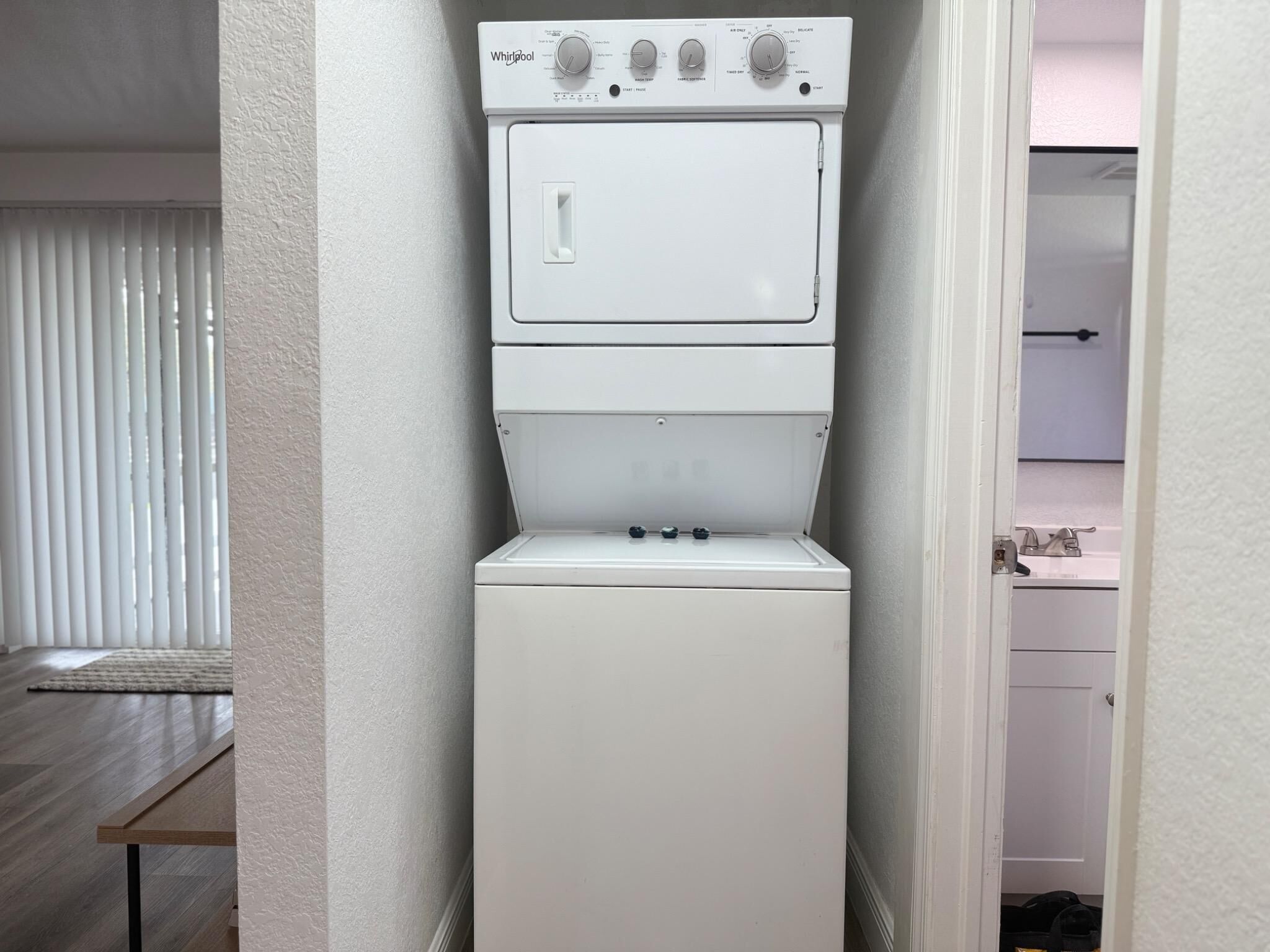 Eine kompakte, weiße Whirlpool Waschmaschine und Trockner-Kombination in einem schmalen Flur.