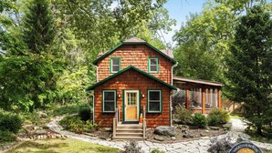 A two-story wooden house with a green roof, a front porch, and a stone pathway leading to the entrance. - Lake Geneva Escape 4BR Arcade Fire Pit and Deck (Lake Geneva)