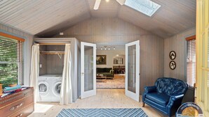 A spacious room with a high ceiling, a laundry area, a blue patterned rug, and a leather sofa. - Lake Geneva Escape 4BR Arcade Fire Pit and Deck (Lake Geneva)