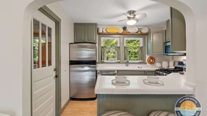 A compact kitchen with a refrigerator, stove, and a window with curtains. - Lake Geneva Escape 4BR Arcade Fire Pit and Deck (Lake Geneva)