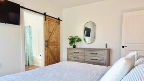 Une chambre à coucher avec un lit, une armoire en bois, un miroir et une plante.