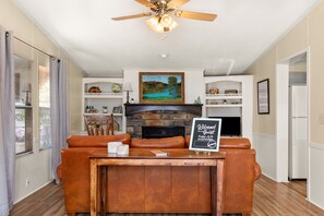 A cozy living area with a fireplace, a wooden bar, and leather seating. - Firefly Lakehouse 3 br, 2 Bath, pet Friendly (Canyon Lake)