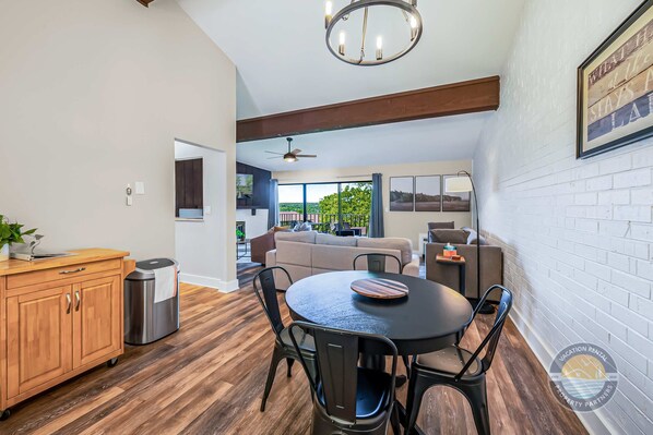 A modern kitchen with a dining area, wooden cabinets, a round table, and a ceiling fan.