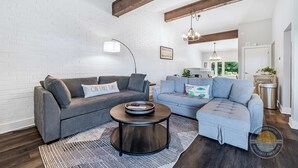 A modern living room with two sofas, a coffee table, and a brick wall. - Modern Lake Geneva Condo With Pool and Patio (Lake Geneva)