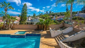 A swimming pool with a clear blue water, surrounded by a brick wall and a concrete deck. - Marbella Lane - Revitalizing Getaway w Pool (Rowland Heights)