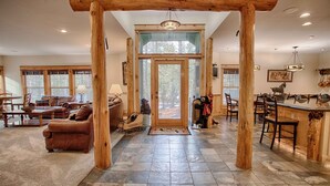 A spacious living area with a stone floor, wooden beams, a large window, and a cozy fireplace. - Red Fir 14 (Bend)