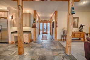 A spacious hallway with wooden beams, a kitchen with a refrigerator, and a dining area with a lamp. - Red Fir 14 (Bend)