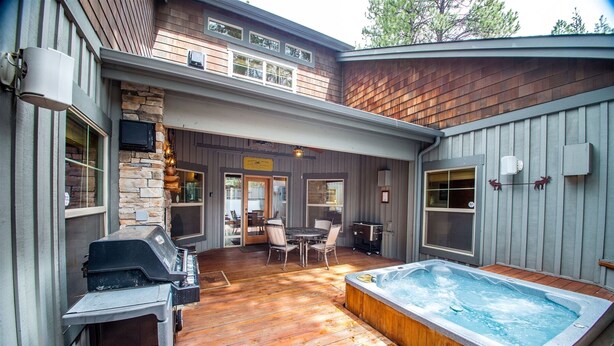 A backyard with a hot tub, a barbecue grill, and a dining area with outdoor furniture. - Red Fir 14 (Bend)