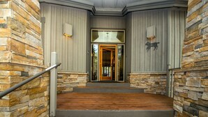 A staircase leading to a wooden door with a glass panel, flanked by stone walls and a metal handrail. - Red Fir 14 (Bend)