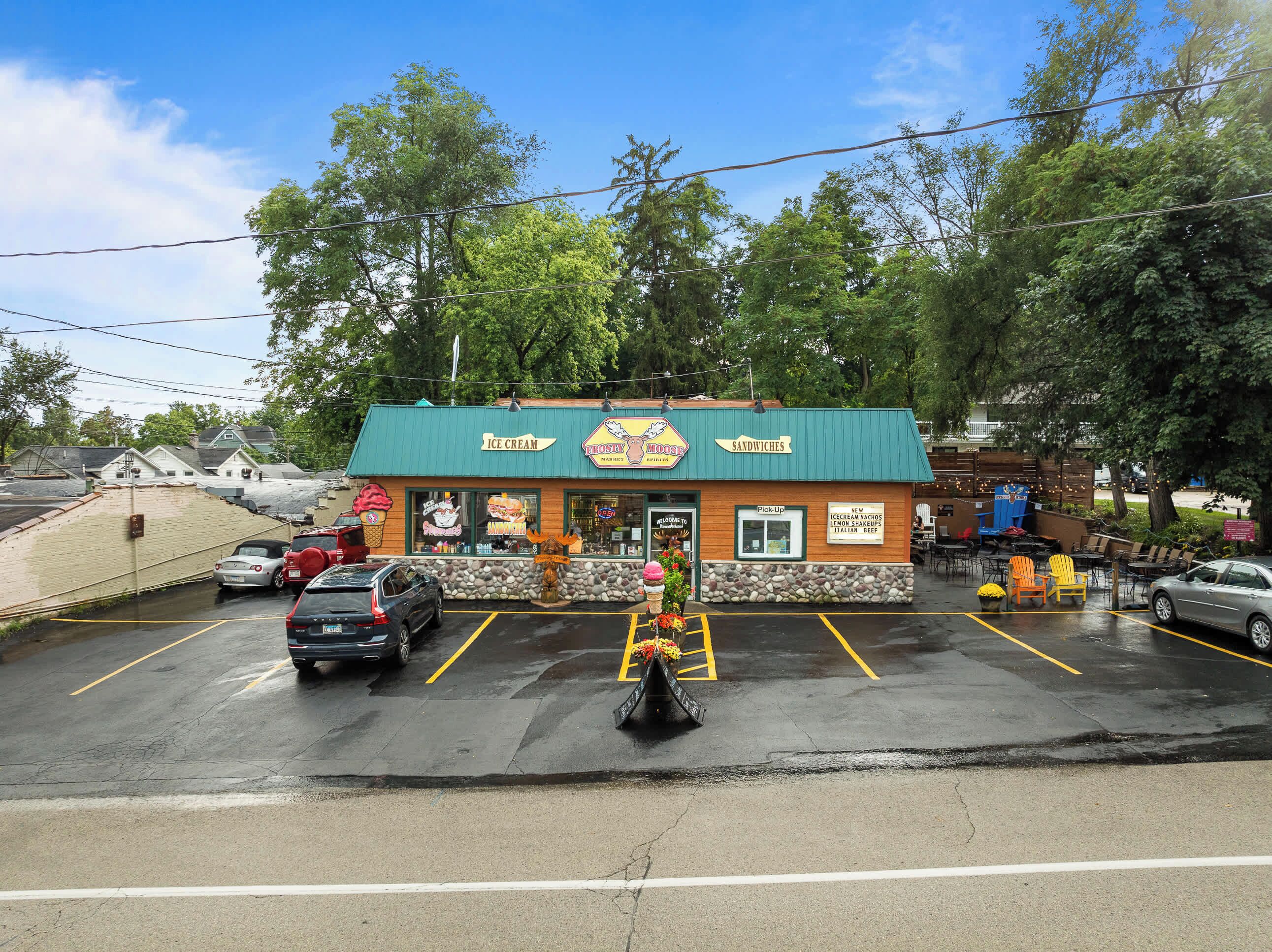 A restaurant with a green roof and a signboard advertising ice cream and sandwiches.