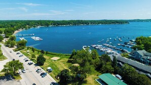 A marina with boats docked, a road with parked cars, and a building with a green roof. - Lakeside Family Home Walk to Beach (Williams Bay)