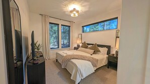 A bedroom with a large bed, two windows, a ceiling light, and a TV. - Pine Mountain 6 (Bend)