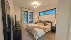 Ein Schlafzimmer mit einem großen Bett, zwei Fenstern, einer Deckenleuchte und einem Fernseher.