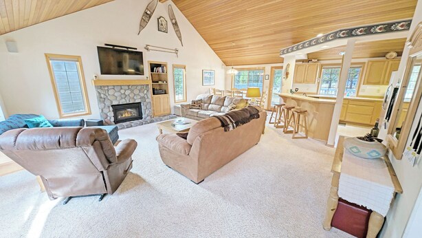 A spacious living room with a fireplace, a television, and a kitchen area with stools. - Snowshoe Inn-pyramid Mtn 7 (Bend)