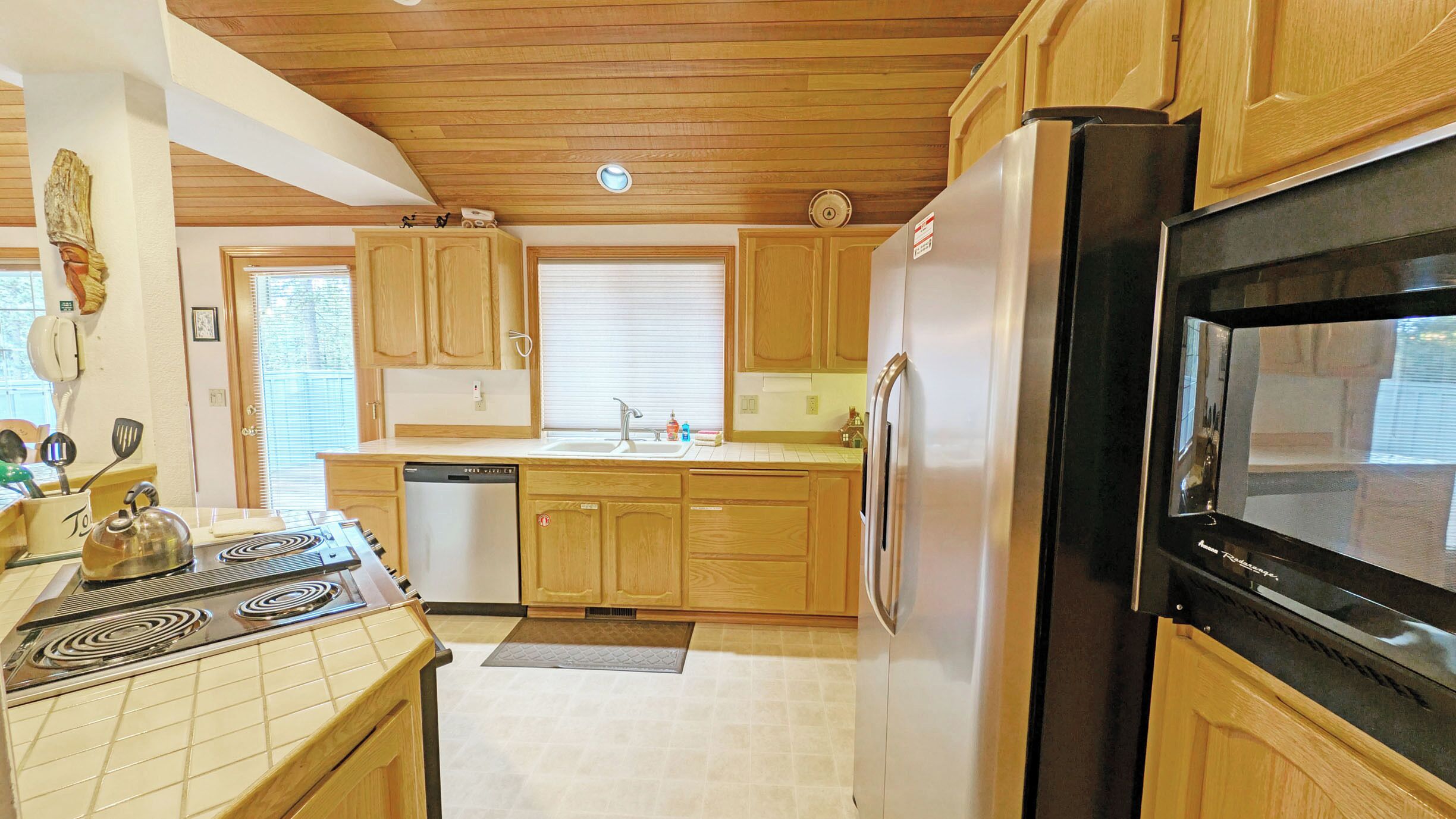 A kitchen with wooden cabinets, a stainless steel refrigerator, a stove, and a dishwasher.