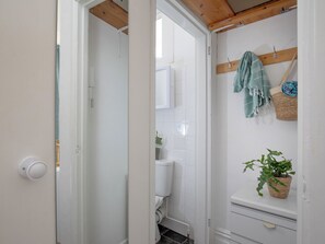 A bathroom with white tiles, a toilet, a sink, a hanging towel, and a potted plant. - Sunny Side - UK51426 (Paignton)