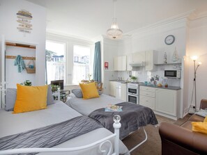 A bedroom with two beds, a kitchenette, and a view of the outside. - Sunny Side - UK51426 (Paignton)