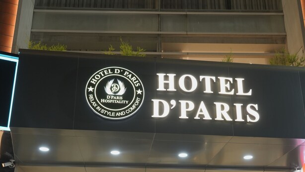 The exterior of Hotel D'Paris with a modern facade, a glass entrance, and a visible reception desk.