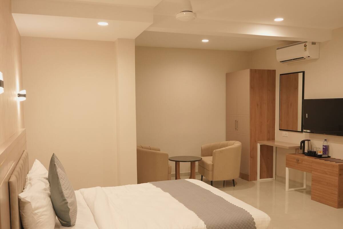 Una habitación de hotel moderna con cama, mesita de noche, escritorio, silla y televisor.