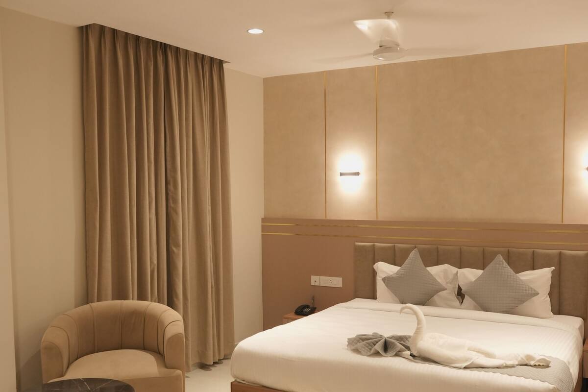 Una habitación de hotel moderna con una cama grande, una silla, una mesita y un ventilador de techo.