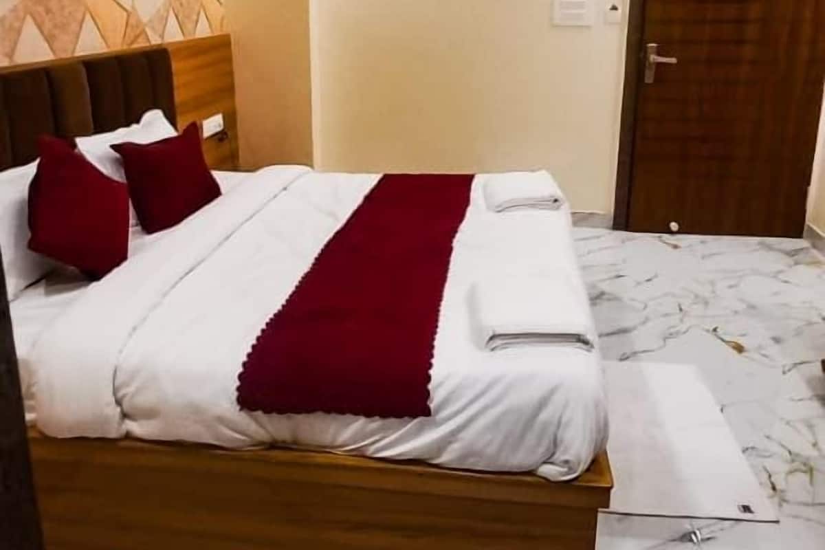 Quarto de hotel com cama, ventoinha no teto, cabeceira de madeira, piso de mármore e uma porta.