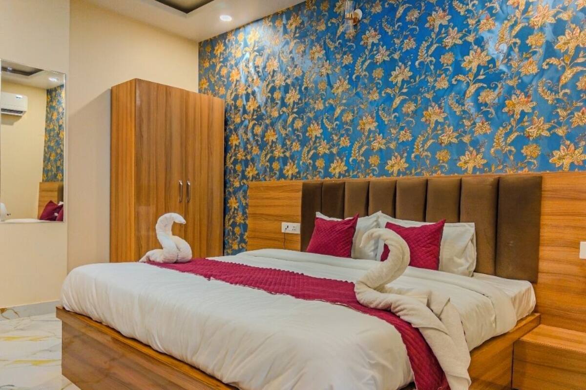 Quarto de hotel com cama grande, guarda-roupa de madeira e papel de parede floral.