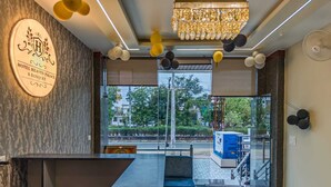 A reception area with a marble counter, a chandelier, and a view of the street outside. - Hotel Heaven Palace And Banquet (Jaipur)