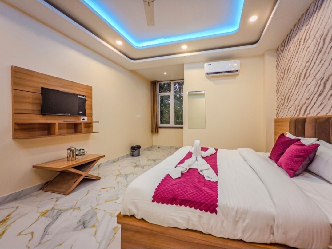 Een moderne hotelkamer met een bed, een televisie, een houten plank en een plafondlamp.
