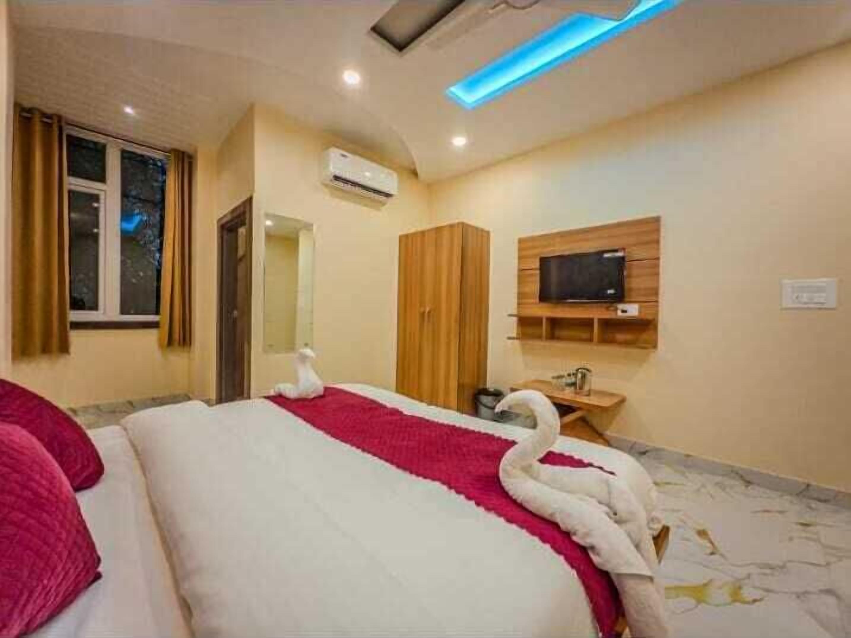 Un dormitorio con cama, televisión, equipo de aire acondicionado y armario de madera.