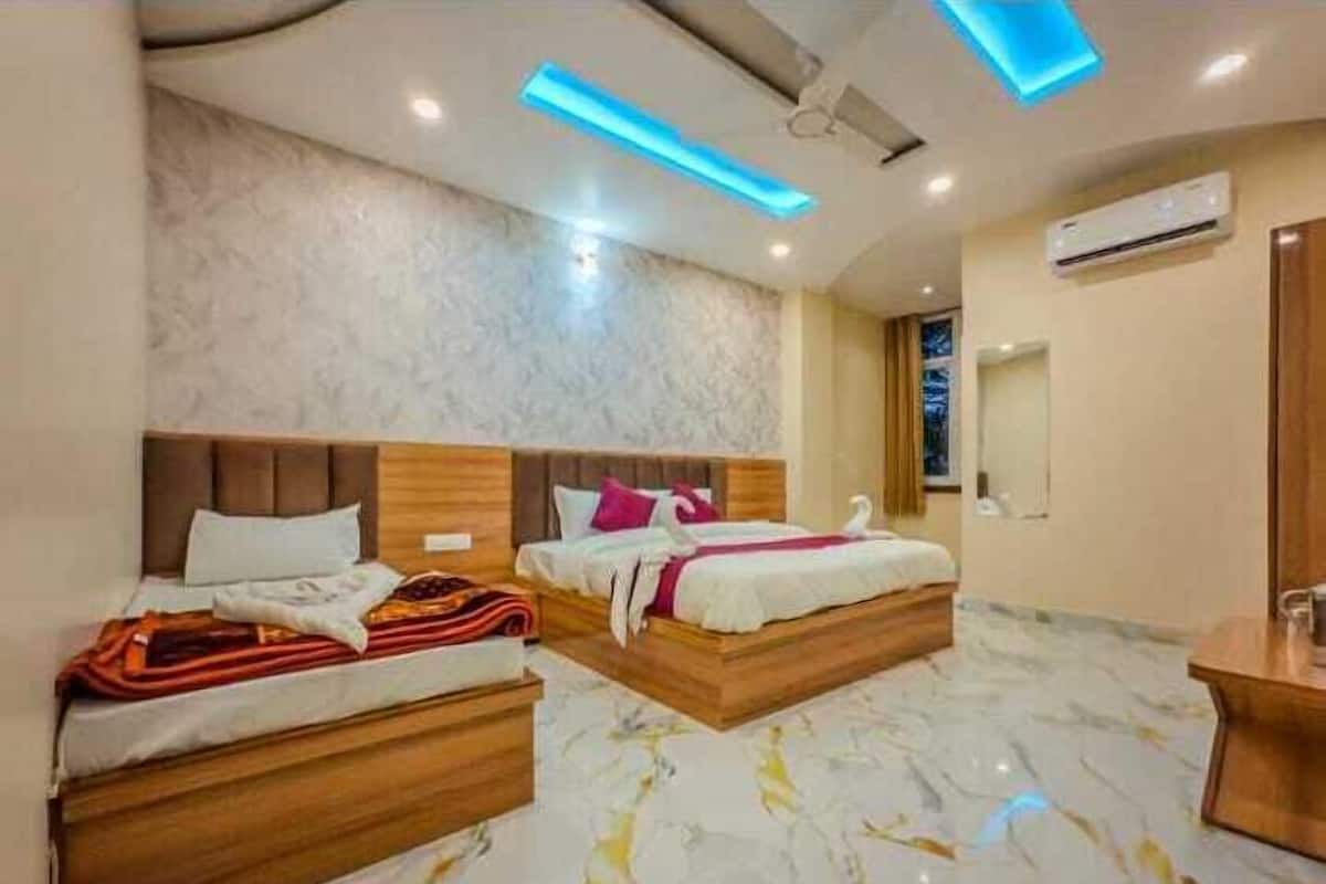 Quarto de hotel com duas camas de madeira, soalho de mármore e iluminação moderna.
