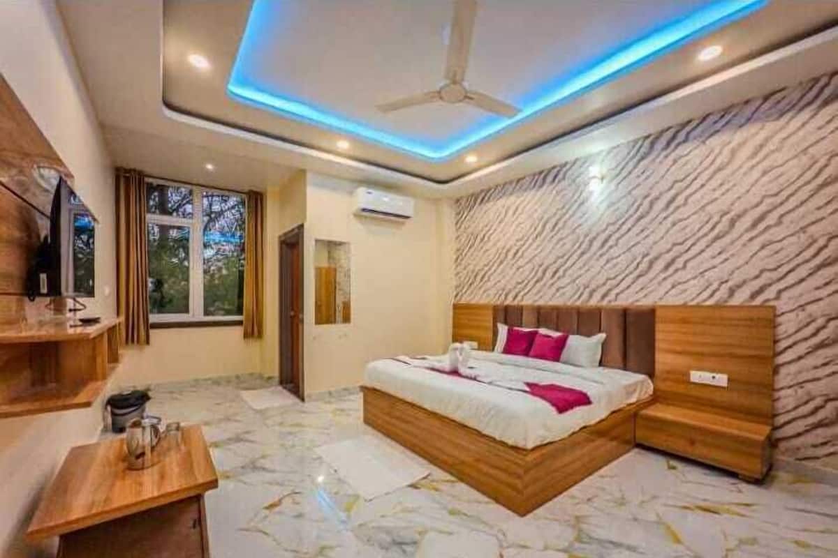Quarto com cama, ventoinha no teto, televisão, janela e piso de mármore.