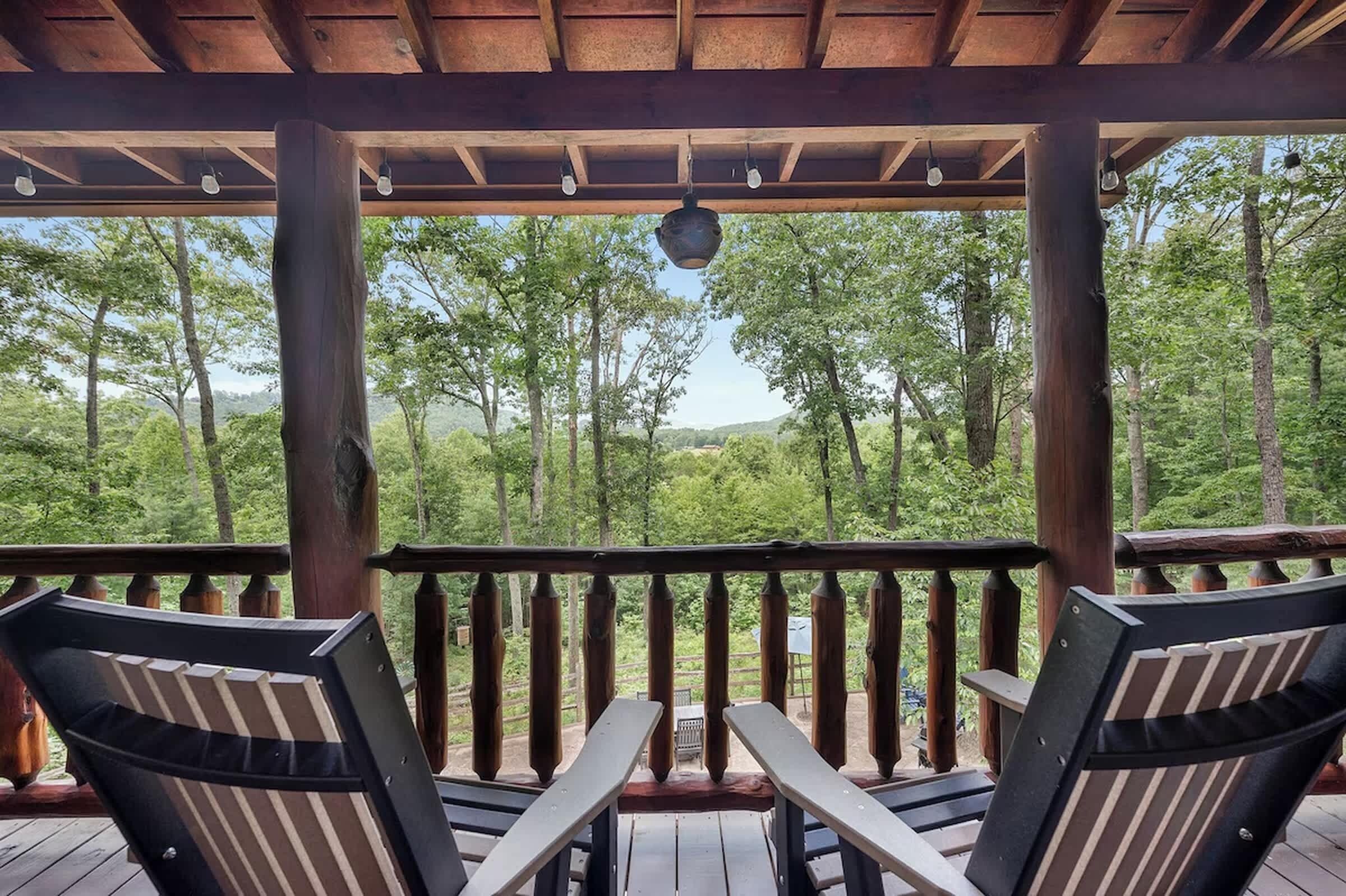 Une terrasse en bois avec deux chaises et une table, donnant sur une zone boisée.