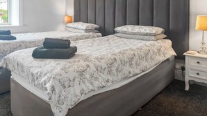 A hotel room with two beds, each with a grey headboard, floral bedding, and a bedside lamp. - 2 bedroom accommodation in Fence (Fence)