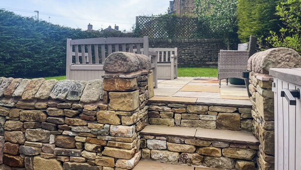 A stone wall, a wooden gate, and a patio area with a stone bench and a table. - 2 bedroom accommodation in Fence (Fence)