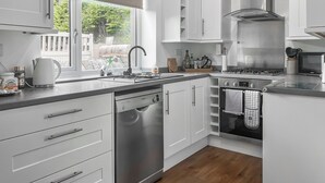 A modern kitchen with white cabinetry, stainless steel appliances, and a window with a view of greenery. - 2 bedroom accommodation in Fence (Fence)