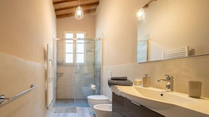 Un baño moderno con cabina de ducha de vidrio, inodoro, lavabo y tocador con espejo.