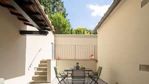Un patio con una mesa, sillas, una pequeña escalera y una barandilla.