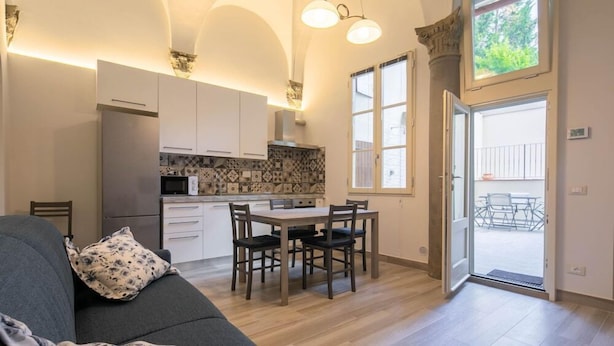 Una cocina moderna con armarios blancos, una mesa de comedor con sillas y un amplio ventanal.