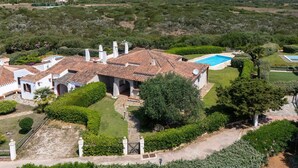 Eine Villa mit Swimmingpool, umgeben von üppiger Vegetation und einer hügeligen Landschaft.