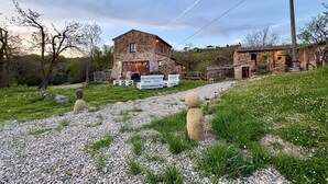 A stone building with a gravel path leading to it, surrounded by greenery and trees. - La Tresa Country Living (Montepulciano)
