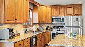 A kitchen with wooden cabinets, a microwave, a stainless steel refrigerator, a coffee maker, and a dishwasher. - Sleeps 20! 2 Lakefront Homes w/ Hot Tub, Firepit, Game Room, Community Amenities (Long Pond)