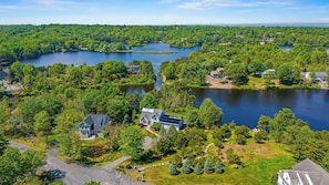 An aerial view of a residential area with houses, a lake, and surrounding greenery. - Sleeps 20! 2 Lakefront Homes w/ Hot Tub, Firepit, Game Room, Community Amenities (Long Pond)