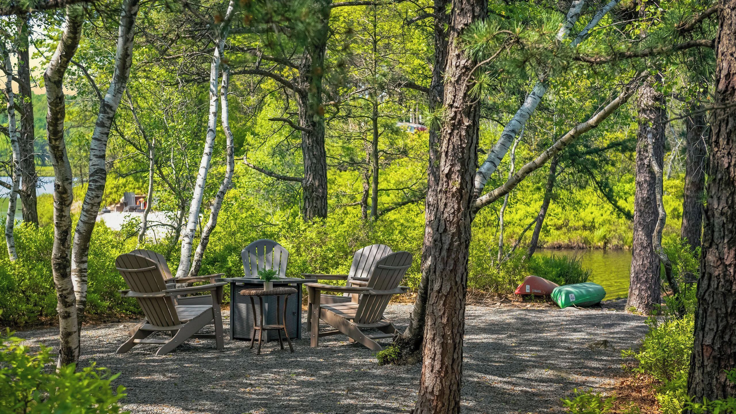 A picnic setup with a table and chairs surrounded by trees.